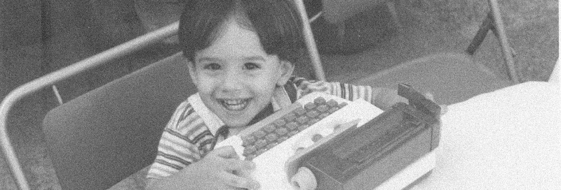 Federico as a child, smiling beside a typewriter
